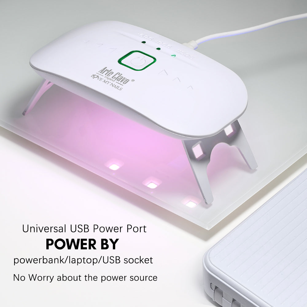 Person using Arte Clavo compact USB nail lamp to cure gel polish at home, travel-friendly design